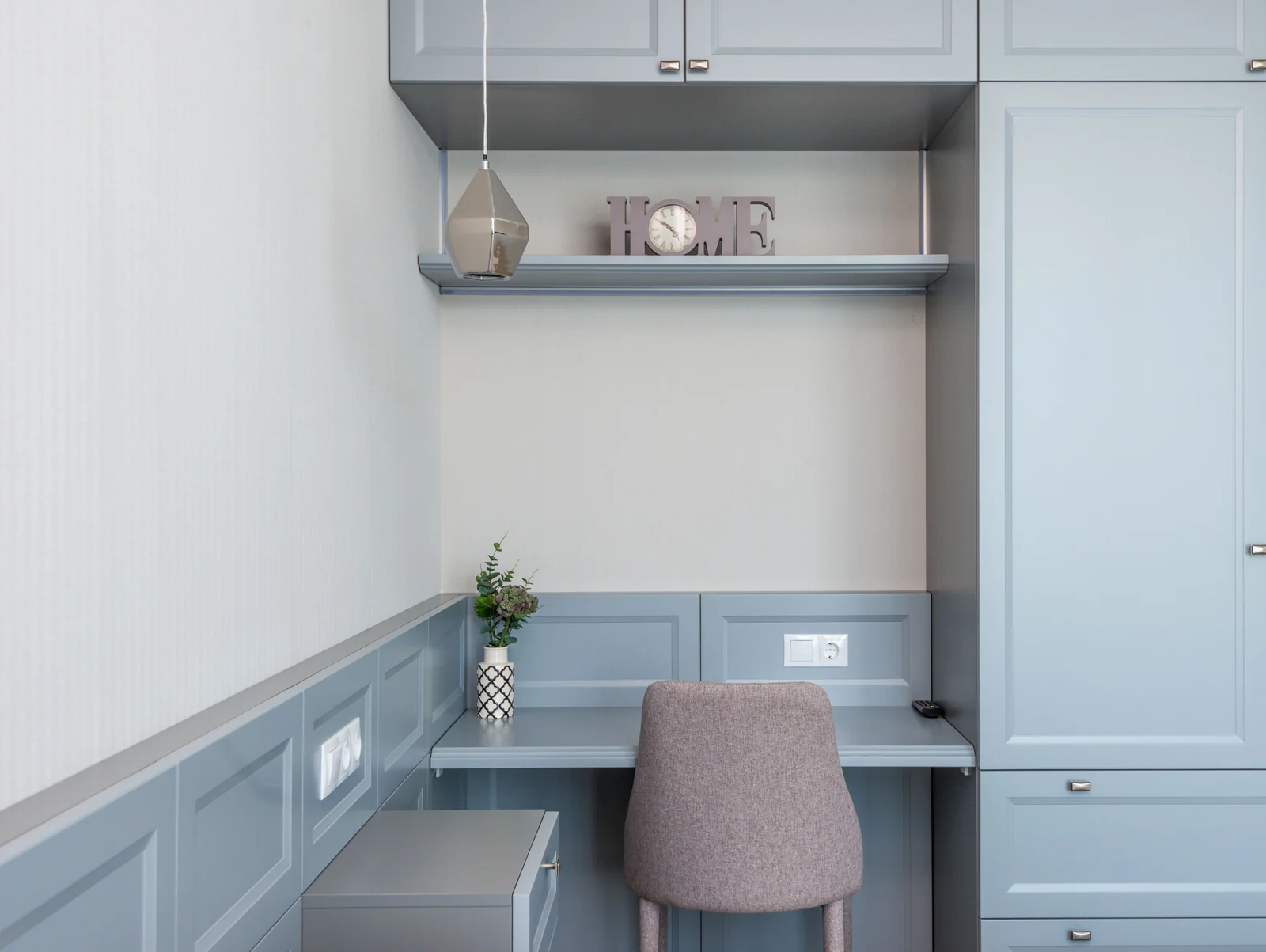 A blue-grey shaker built-in desk with tall storage either side