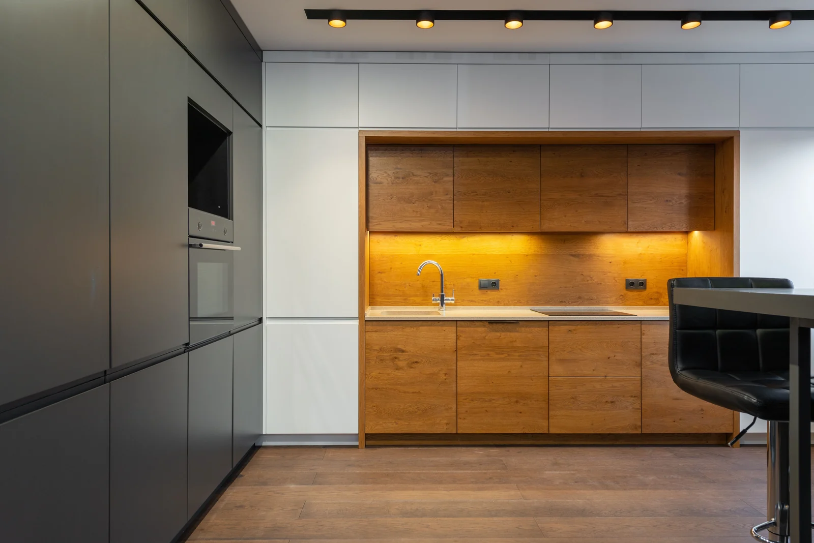 Graphite slab cabinetry with a lit oak alcove