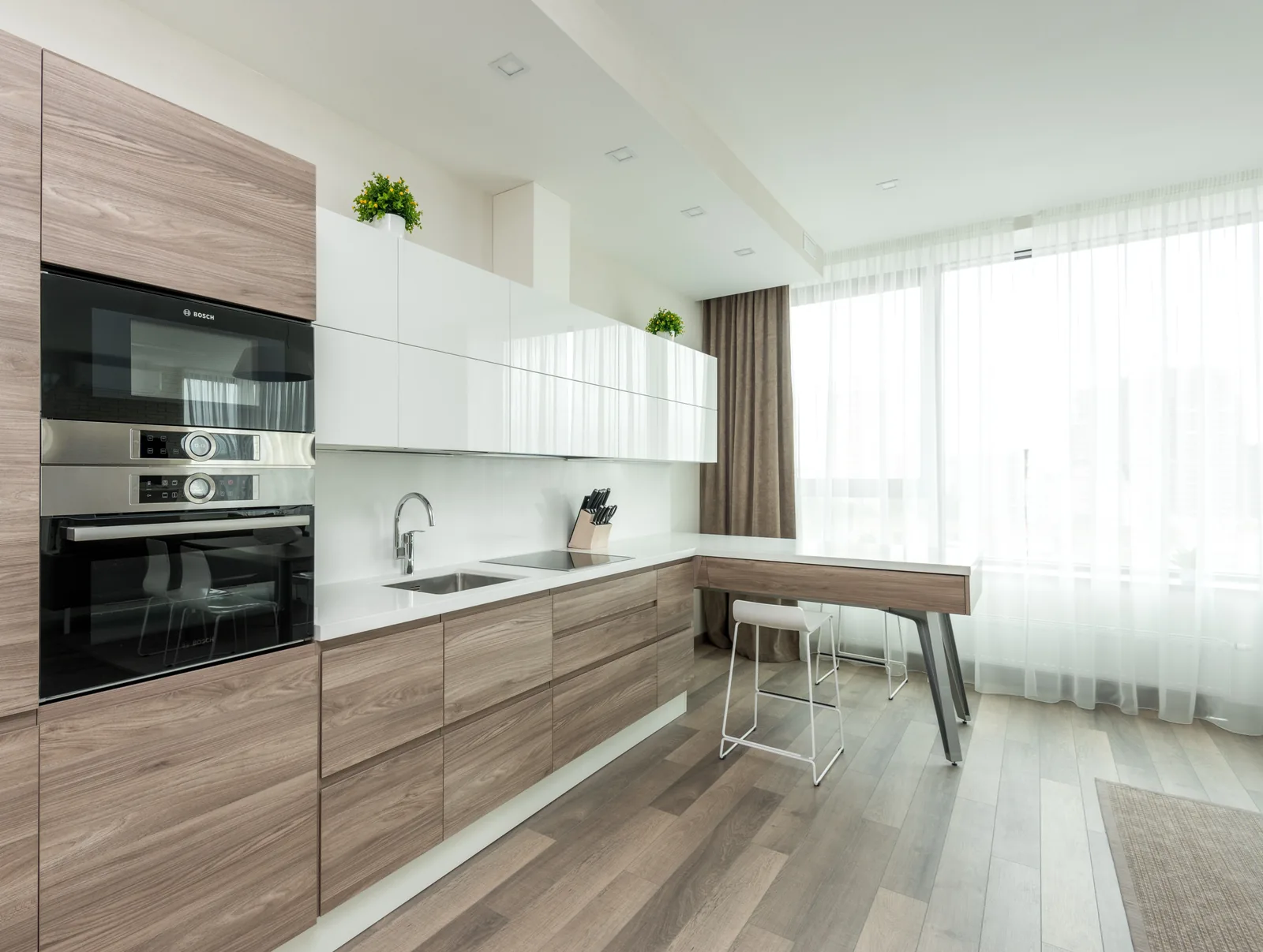 Light wood cabinets with white gloss uppers and a breakfast bar